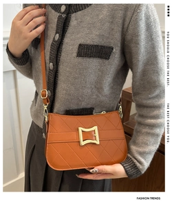 Sac bandoulière marron matelassé avec boucle dorée porté par un mannequin