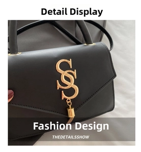 Macro shot of gold metal double S logo and cylindrical pendant on black leather handbag