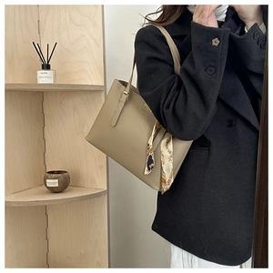 Detail of khaki leather tote bag featuring a decorative printed silk scarf on the handle