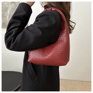 Detail of dark red woven leather texture on hobo bag with classic intrecciato pattern