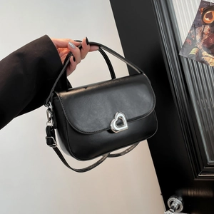 Chic black saddle bag with silver heart lock shown in a minimalist setting