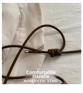 Detail of soft brown leather handbag handle with knot decoration and silver buckle
