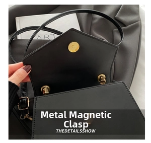 Close-up of black envelope crossbody bag with shiny gold magnetic snap closure hardware