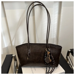 Detail of dark brown vintage tote bag with PU leather texture and tennis racket charm