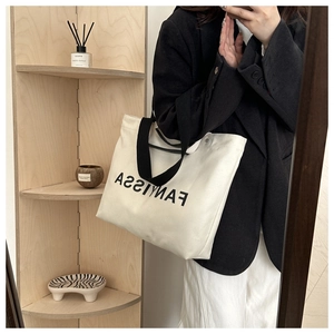 Detailed shot of large cream canvas tote bag with black Fanyissa logo and wide handles