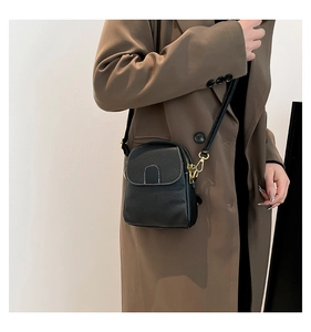 Detail of black litchi texture leather crossbody bag with white contrast stitching