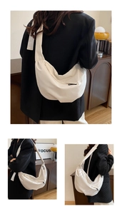 Close-up of white half-moon crossbody bag with wide shoulder strap and zip closure