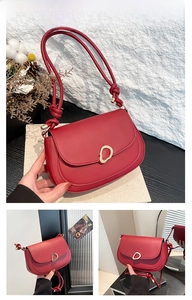 Detail of red saddle bag featuring woven knot strap and round gold metal buckle