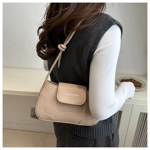 Detail view of beige crossbody bag with knotted shoulder strap worn by a model