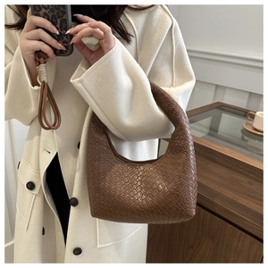 Close-up of caramel brown woven leather texture on a stylish half-moon hobo bag detail