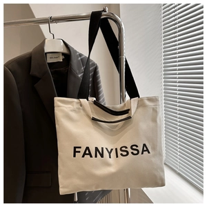 Detail of canvas tote bag with black FANYISSA lettering and reinforced shoulder straps