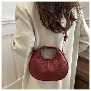 Detail of burgundy woven crescent bag showing leather texture and adjustable strap