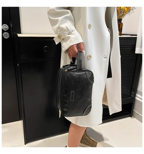 Détail d'une trousse de toilette rectangulaire en similicuir noir avec surpiqûres blanches