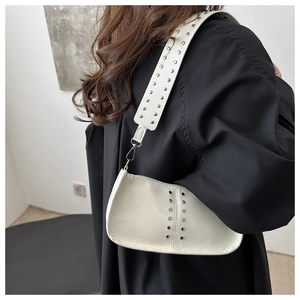 Gros plan d'un sac demi-lune blanc avec des rivets métalliques argentés sur la bandoulière