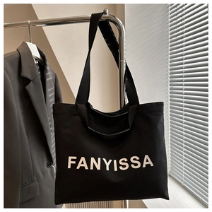 Detail of black canvas tote bag with FANYISSA lettering and versatile shoulder strap