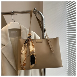 Detail of khaki tote bag with fashion metal logo and silk scarf on metal hanger