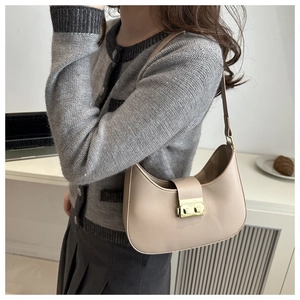 Detail of beige crescent underarm bag showing litchi texture and gold buckle hardware