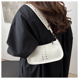 Gros plan sur le sac demi-lune en similicuir blanc orné de clous argentés et rivets