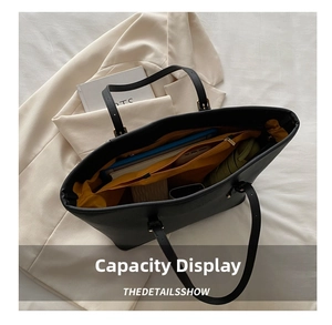 Interior view of black tote bag showing spacious yellow lining and laptop storage