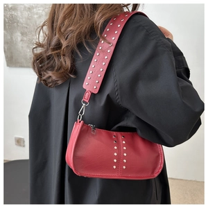 Gros plan d'un sac sous le bras rouge avec clous argentés porté par un mannequin