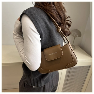Detail of brown shoulder bag with Fashion & Bags text and decorative knot strap design