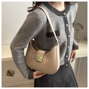 Detail of minimalist beige crescent hobo bag with a polished gold rectangular metal lock