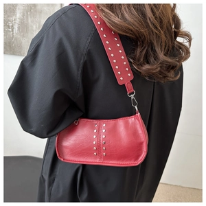 Gros plan d'un sac à bandoulière rouge avec clous argentés et cuir brillant
