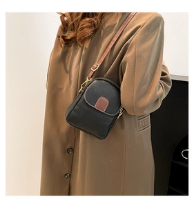 Detail showing cross-body wear of black lychee leather mini bag with gold metal buckle