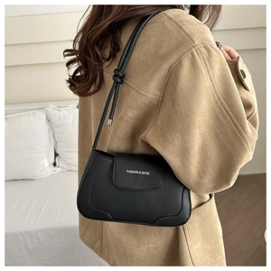 Detail of black leather underarm bag featuring knotted strap and white logo text