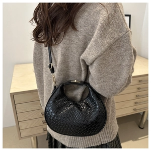 Detail of black woven crescent bag featuring gold metal hardware and adjustable strap