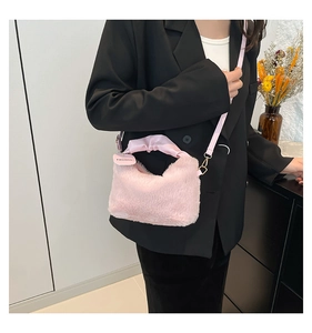 Pink plush handbag detail with silk handle and Fashion tag worn over black blazer