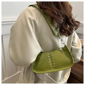 Détail du sac à bandoulière en cuir vert avocat avec clous argentés sur la large sangle