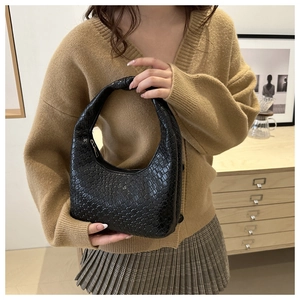 Detail of black woven leather hobo bag with knotted handle and elegant knitwear outfit