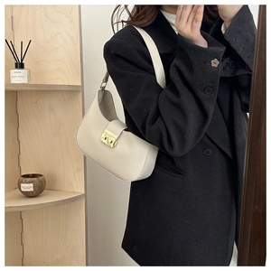 Detailed view of cream hobo shoulder bag with a vintage gold buckle on a black blazer