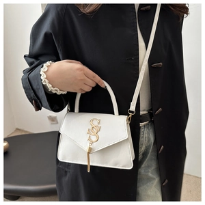 Detail of white leather handbag with golden tassel and metal logo on the envelope flap