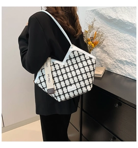 Detail of black and white tweed tote bag with elegant white leather trim and side ribbon