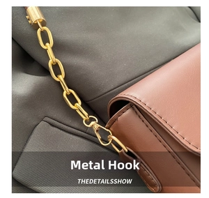 Close-up of golden hardware chain and swivel hook on a vintage brown leather bag