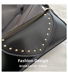 Close-up of black PU leather underarm bag featuring gold rivets and curved flap design