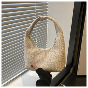Detail of woven faux leather texture and knotted handle on a cream white hobo tote bag