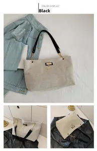 Detail of beige canvas tote bag with black leather straps and gold deer pendant