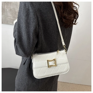 Détail d'un sac bandoulière blanc matelassé avec boucle dorée porté par un mannequin