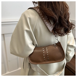 Détail de sac à bandoulière en PU marron avec rivets argentés et large sangle