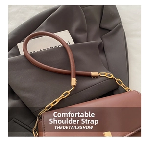 Detail of a brown leather crossbody bag with golden chain and metallic buckle hardware
