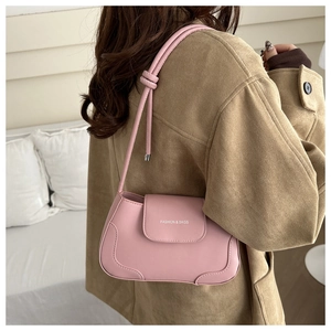 Detailed close-up of a pink faux leather underarm bag with decorative knotted shoulder strap
