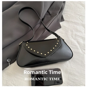 Detail view of black vintage underarm bag with gold studs and smartphone size reference