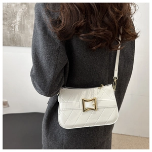 Détail macro du motif matelassé blanc sur le sac à bandoulière avec boucle dorée