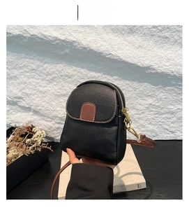 Detail of mini black and brown crossbody bag with lychee leather texture and gold zipper