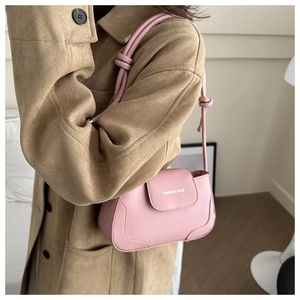 Close-up of pink faux leather underarm bag with knotted shoulder strap detail
