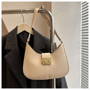 Detail of minimalist beige half-moon shoulder bag with sleek gold-tone metal buckle