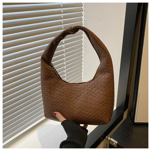 Detailed view of brown hand-woven texture and knotted handle on hobo tote bag